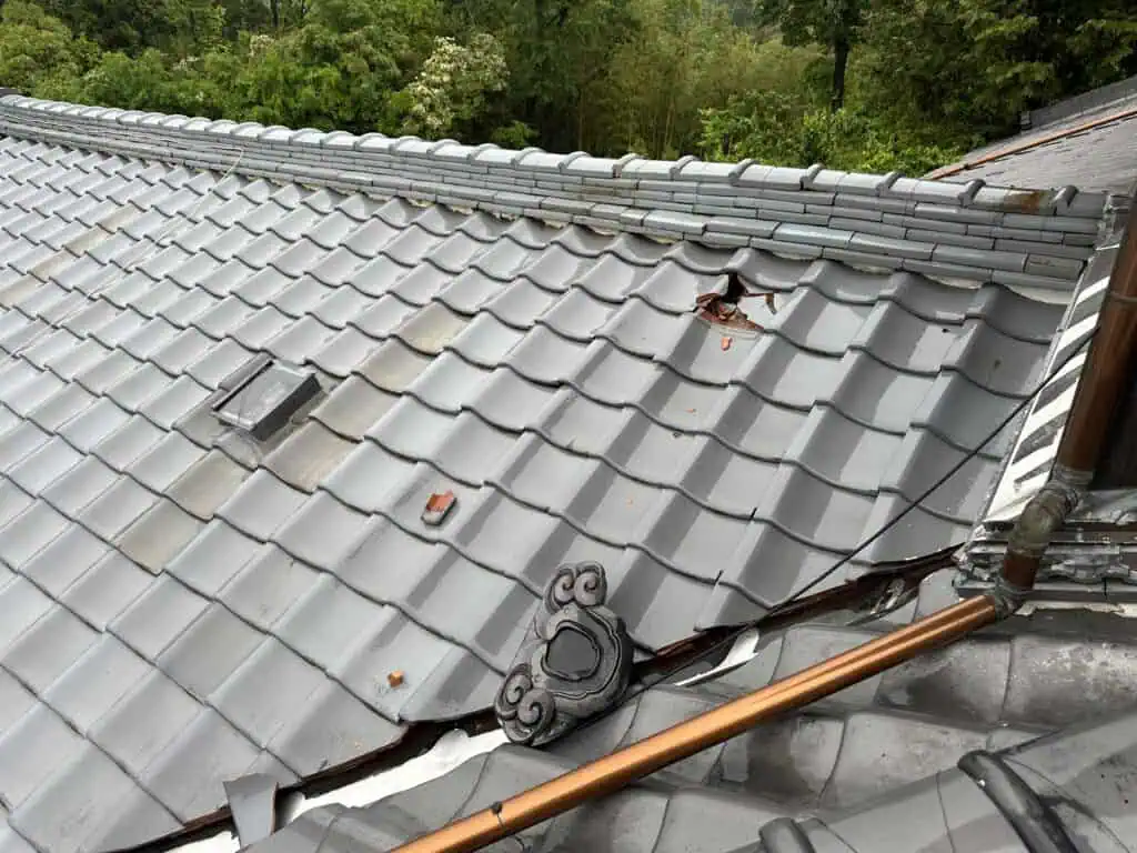 上の屋根の瓦が落下して下の屋根の瓦が破損した様子。この屋内側で雨漏りが発生した。